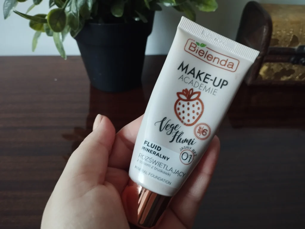 Bielenda Make-Up Academie Vege Flumi Fluid mineralny rozświetlający 01 Jasny Beż trzymany w kobiecej dłoni