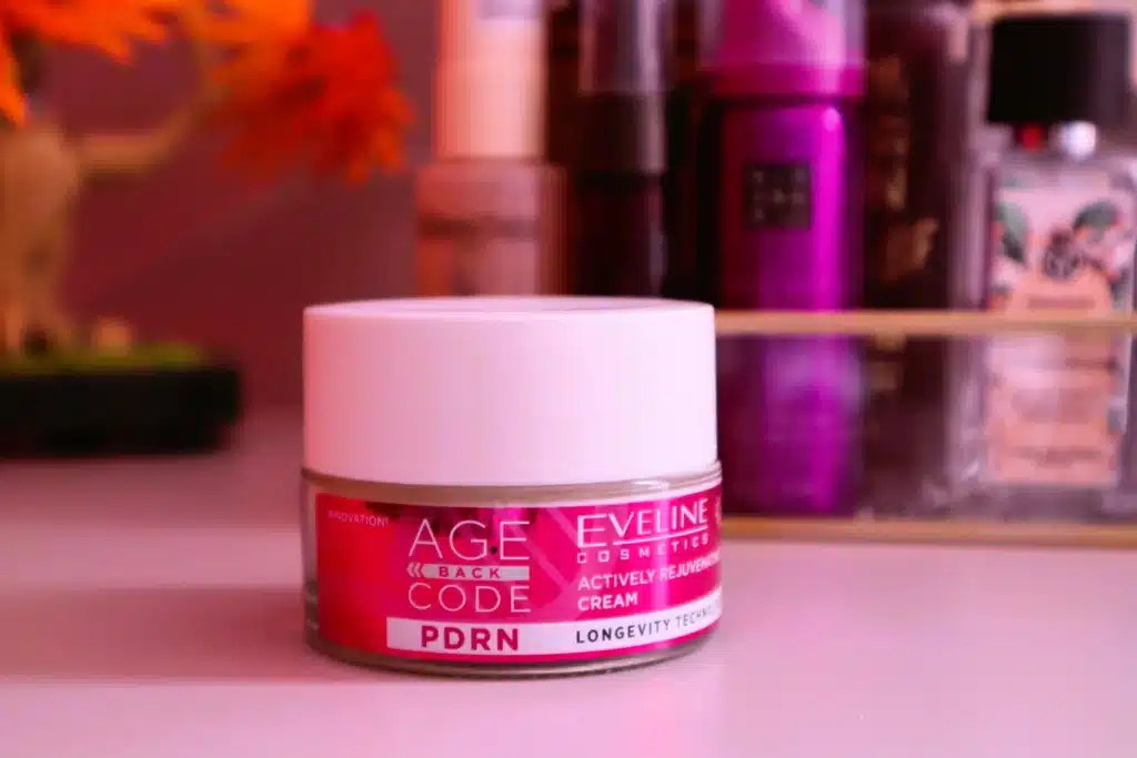 Eveline Cosmetics Age Back Code Krem do twarzy, aktywnie odmładzający, na dzień i na noc stojący na toaletce, w tle kosmetyki
