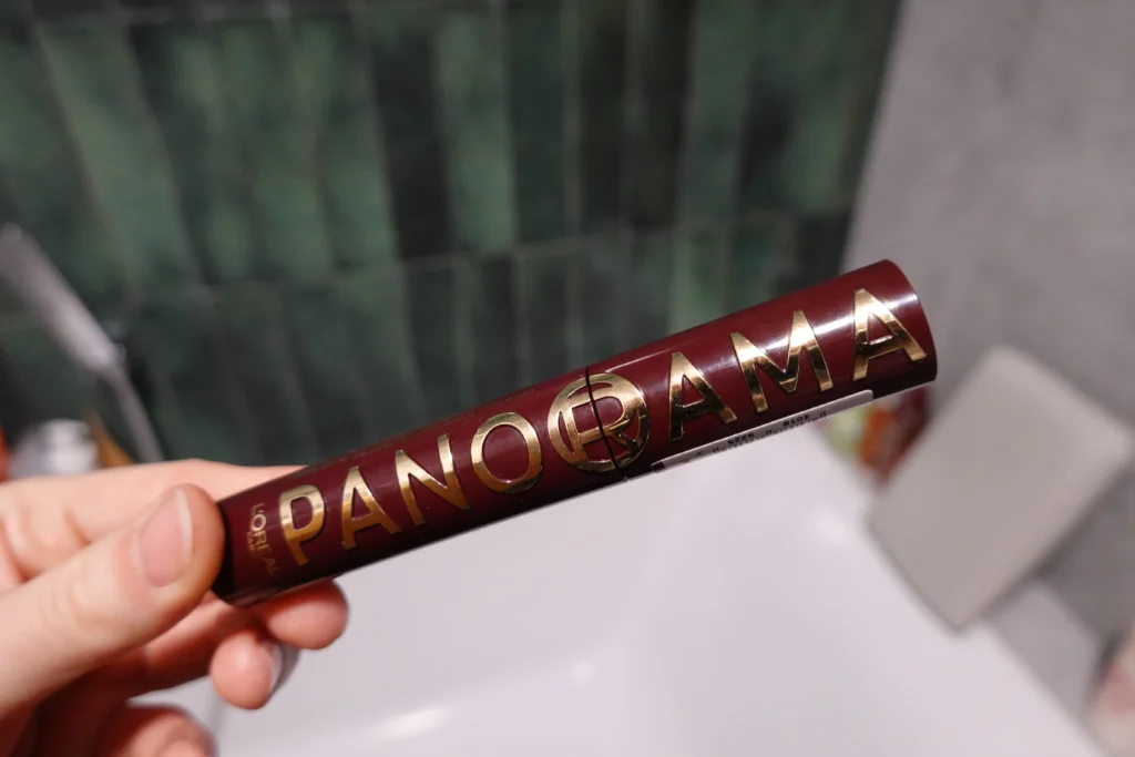 L'Oréal Paris Panorama Tusz do rzęs (Bordeaux Cashmere) trzymany w kobiecej dłoni w łazience