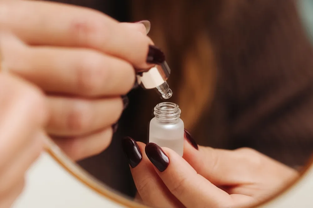 Zbliżenie na kobiece dłonie trzymające buteleczkę serum z retinolem