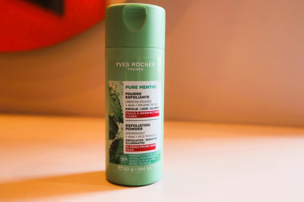 Yves Rocher Puder złuszczający do twarzy na tle beżowej ściany