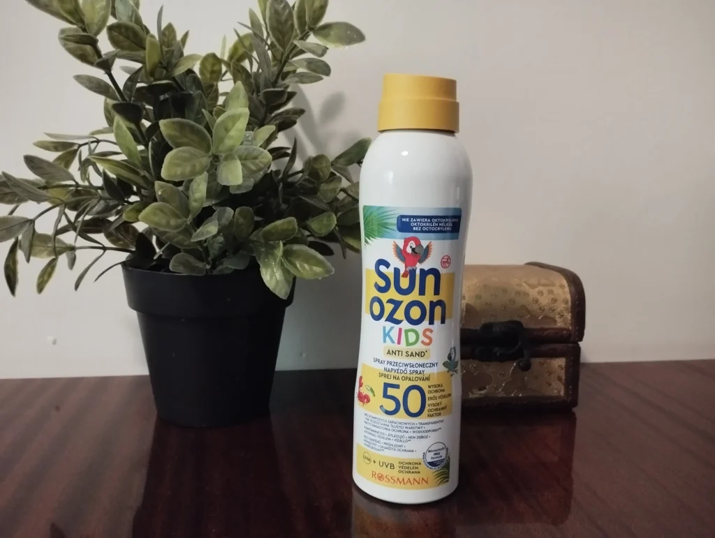 Sunozon Kids Spray przeciwsłoneczny dla dzieci wodoodporny UVA/UVB SPF 50 na komodzie, obok roślinka i szkatułka na biżuterię