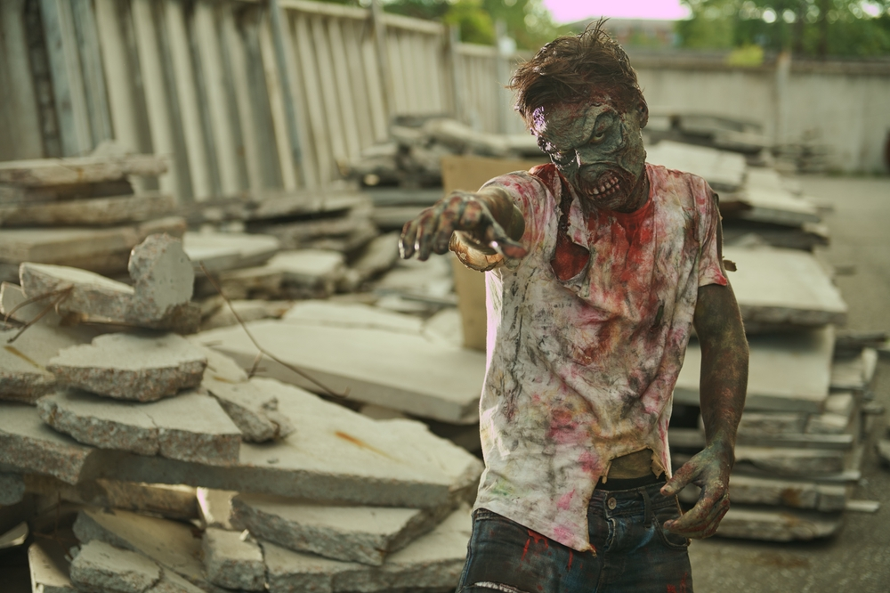 Makijaż zombie w pełnej charakteryzacji — sinozielona baza, sczernione oczodoły i rana na policzku