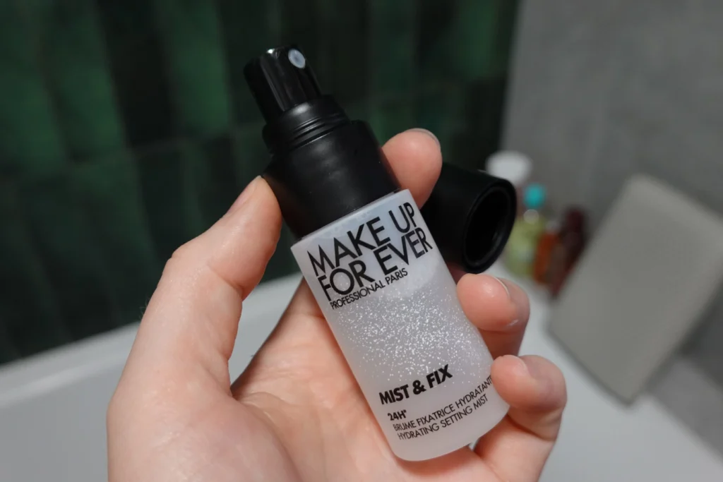Make Up For Ever Mist & Fix Mini mgiełka utrwalająca pod makijaż - wersja podrózna trzymana w kobiecej dłoni